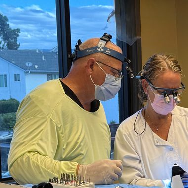 Dr. Janette and a surgical assistant operating with loupes and headlamps